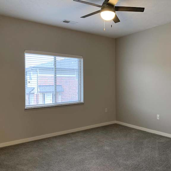 spacious carpeted bedroom with large window allowing a lot of natural light in at the villas at mahoney park