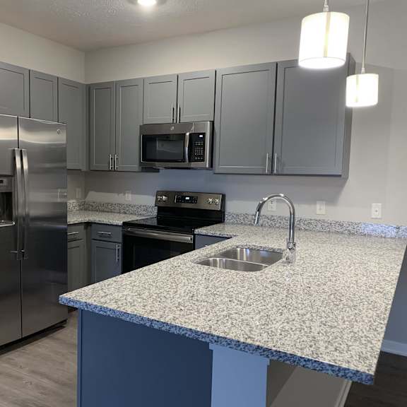 kitchen with slate gray cabinets and matching stainless steel appliances at the villas at mahoney park