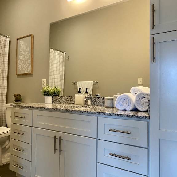 Thumbnail 6 of 16 A bathroom with a white toilet, a white sink, and a white shower curtain.