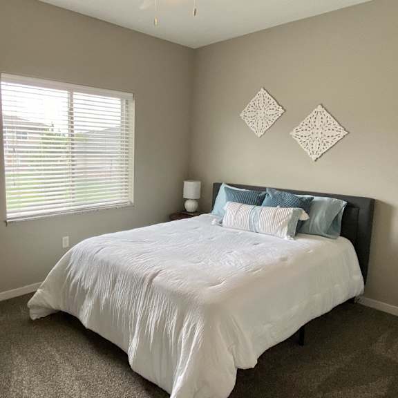Thumbnail 5 of 16 A bedroom with a white bed and a mirror on the wall.