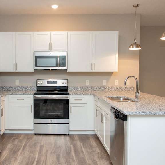 Thumbnail 6 of 17 A kitchen with white cabinets and a granite countertop.
