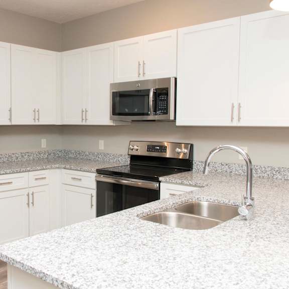 Thumbnail 7 of 17 A kitchen with a stainless steel refrigerator and a granite countertop.