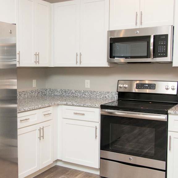 Thumbnail 8 of 17 A kitchen with a stainless steel refrigerator, microwave, and oven.