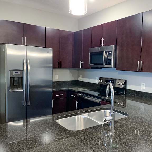 Thumbnail 18 of 21 A kitchen with a granite counter top and stainless steel appliances.