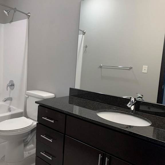 Thumbnail 21 of 21 A bathroom with a white toilet and a black counter top.