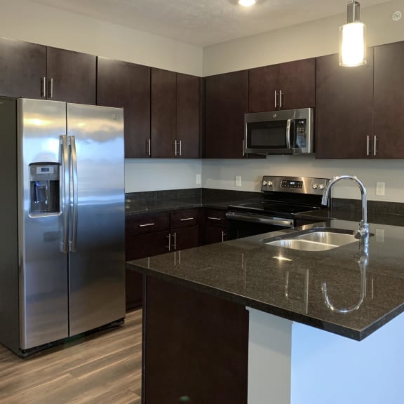 Thumbnail 4 of 26 Kitchen with dark brown cabinets and matching stainless steel appliances in a the grand canyon floorplan at the villas at mahoney park