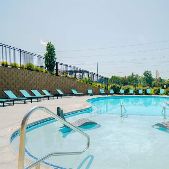 a resort-style pool with two lounge chairs in the  shallow wading are of the water