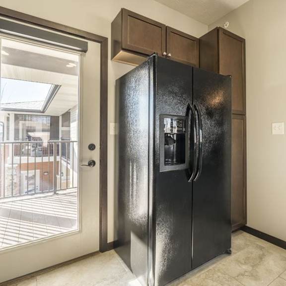 Thumbnail 4 of 11 A black refrigerator is in a kitchen with a white door.
