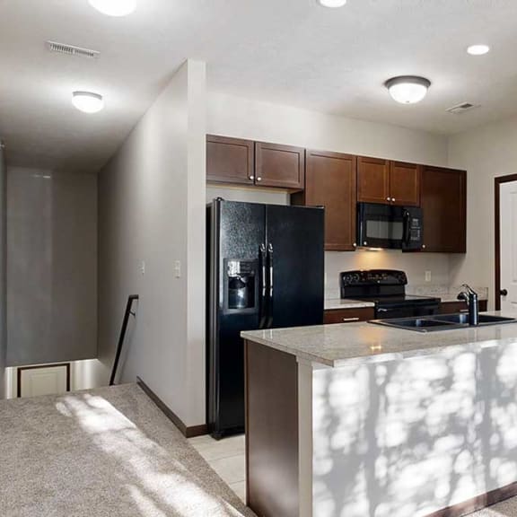 Thumbnail 4 of 22 a galley kitchen with a granite countertop, dark wooden cabinets, and black appliances