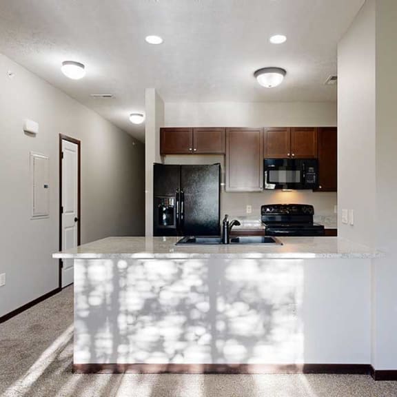 Thumbnail 3 of 22 a kitchen with granite countertops, dark cabinets, and black appliances across from a coat closet