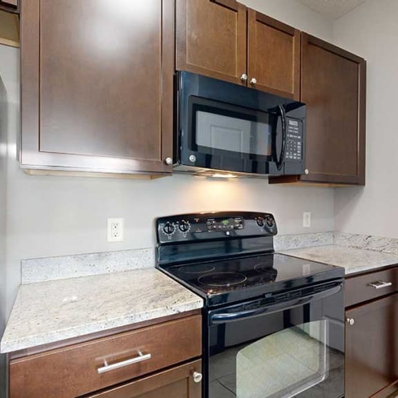Thumbnail 5 of 22 a kitchen with a black stove and microwave and wooden cabinets