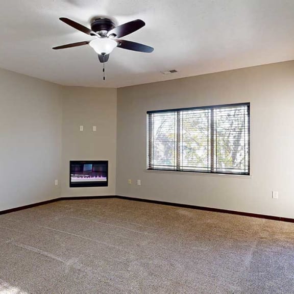 Thumbnail 9 of 22 a carpeted living room with a ceiling fan, a fireplace, a large window, and a door to the balcony