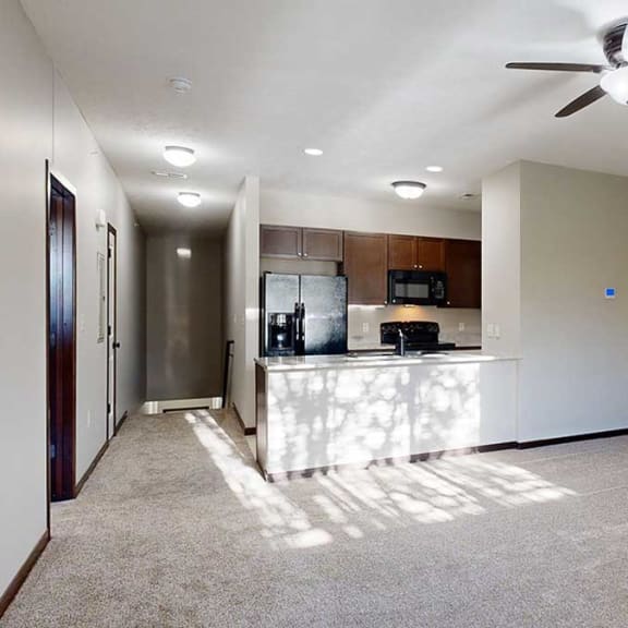 Thumbnail 13 of 22 spacious living area with carpeted flooring, a ceiling fan, and natural light streaming in from nearby windows