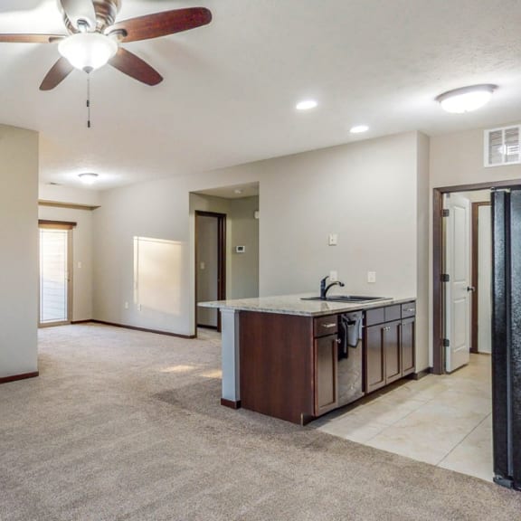 Thumbnail 8 of 19 The kitchen in the Ash overlooks the living space with electric fireplace at The Villas at Wilderness Ridge luxury apartments in southwest Lincoln NE 68512 .