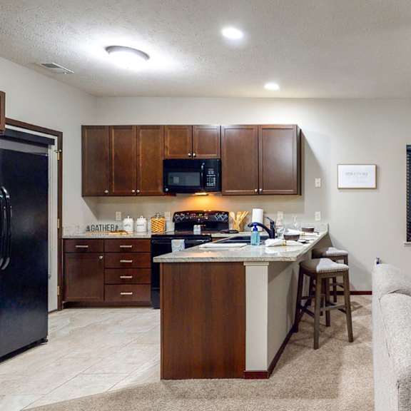 Thumbnail 4 of 19 A kitchen with a refrigerator, microwave, and cabinets.