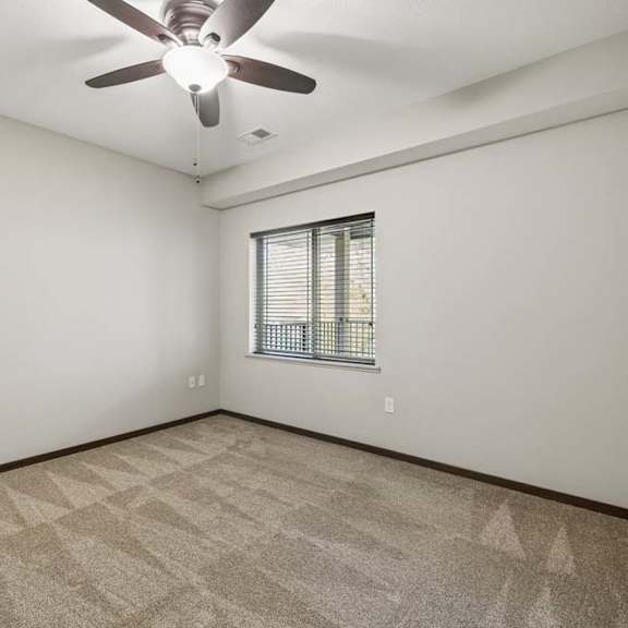 Thumbnail 12 of 30 A room with a ceiling fan and a window with blinds.