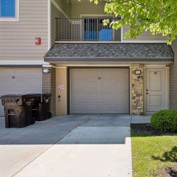 Thumbnail 23 of 40 Apartment exterior with attached garage, front entry, balcony, brick accents, and landscaped lawn.