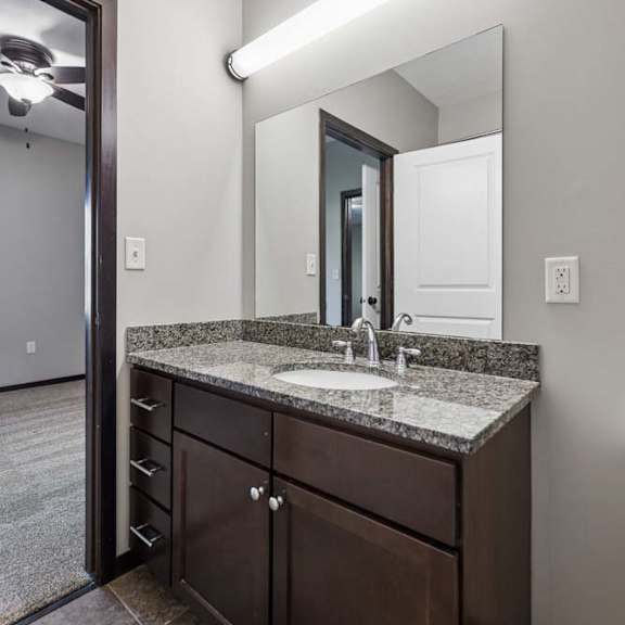 Thumbnail 17 of 19 A bathroom with a sink, mirror, and brown cabinetry.