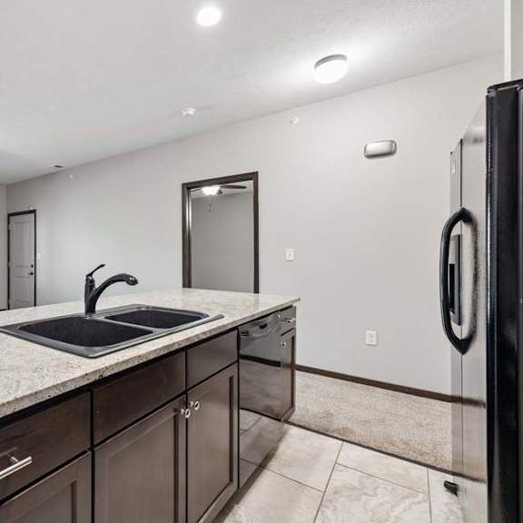 Thumbnail 14 of 19 A kitchen with a sink, a refrigerator, and a ceiling fan.