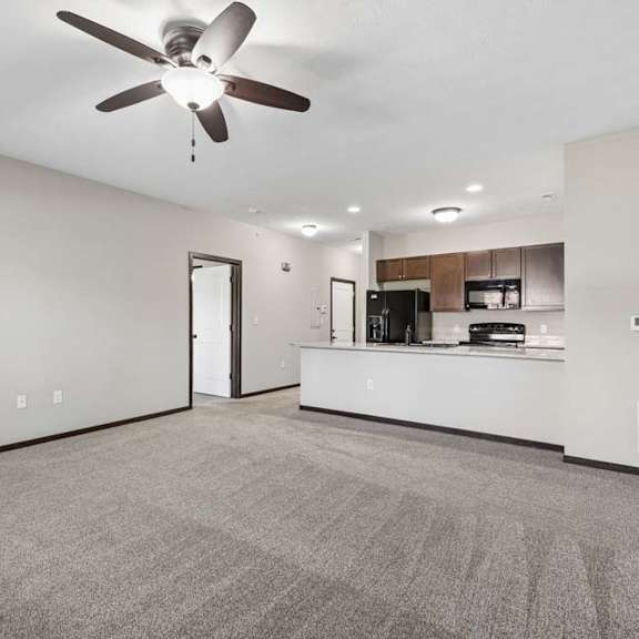 Thumbnail 13 of 19 A spacious room with a ceiling fan and carpeted floor.