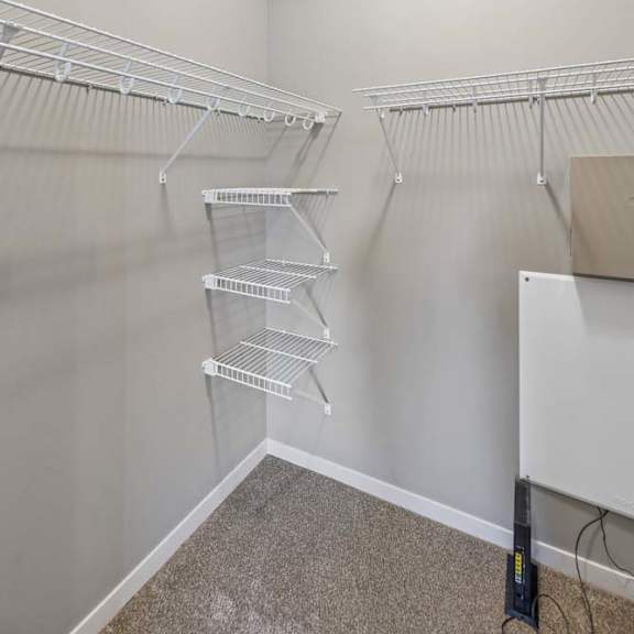 Thumbnail 11 of 16 Walk-in apartment closet with carpet, neutral walls, and wire shelving on multiple sides.