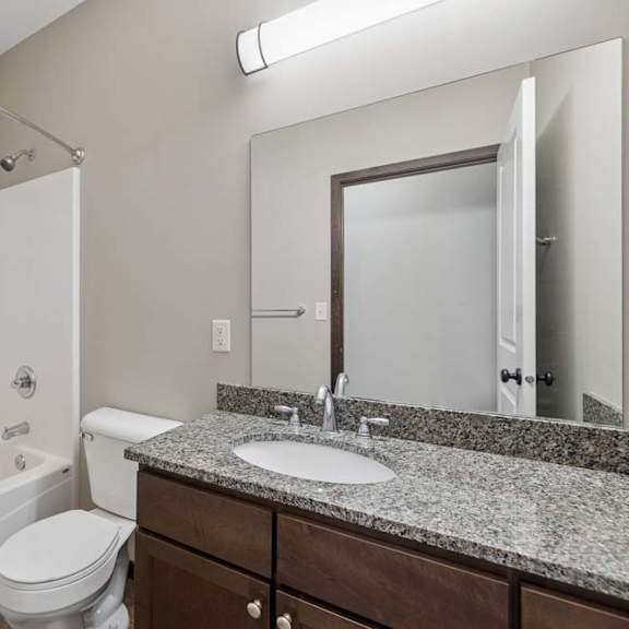 Thumbnail 31 of 59 A bathroom with a white toilet, a white bathtub, and a sink with a mirror above it.
