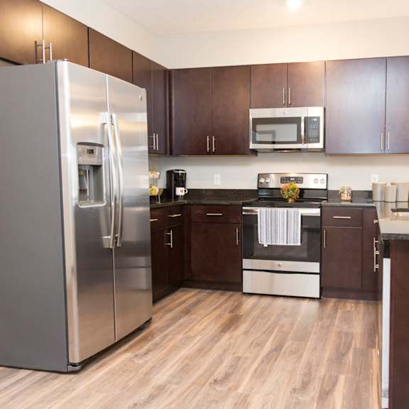 traditional design kitchen with dark cabinetry and granite countertops with stainless steel appliances at villas at mahoney park apartments