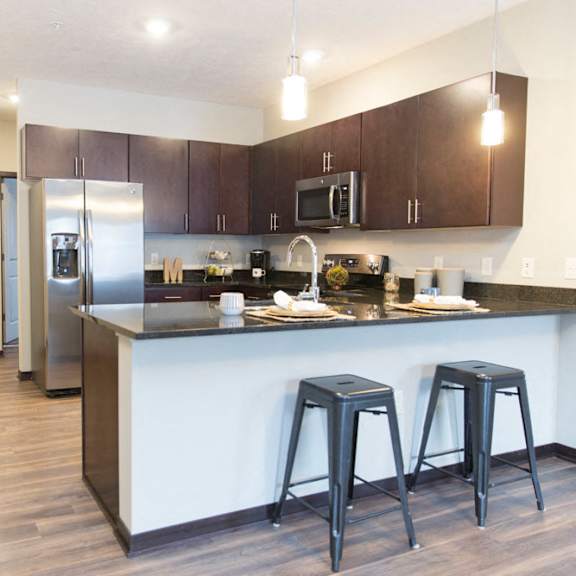 Thumbnail 11 of 17 A kitchen with a white counter and black stools.