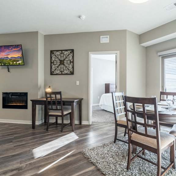 Thumbnail 6 of 23 A dining room with a fireplace and a television mounted on the wall.