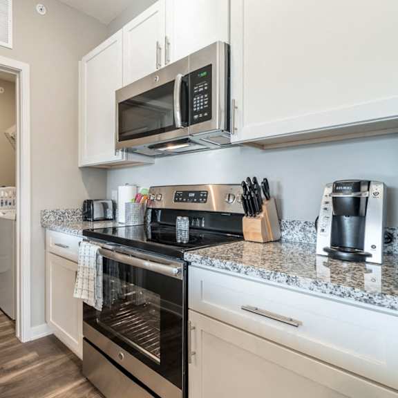Thumbnail 7 of 23 A kitchen with a stove top oven and microwave.