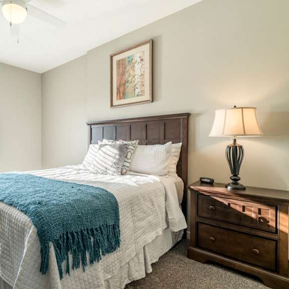 Thumbnail 11 of 23 A bedroom with a bed, nightstand, and a ceiling fan.