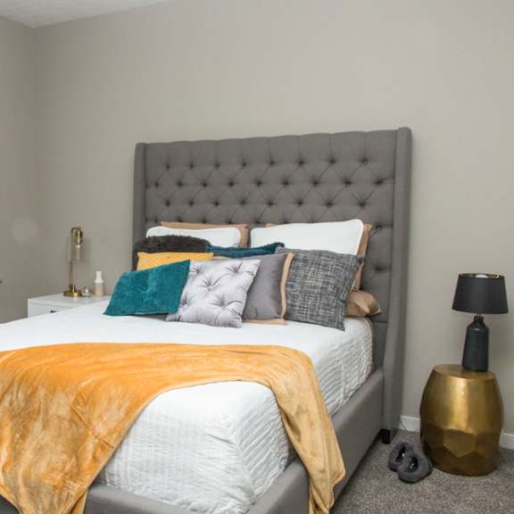 Thumbnail 9 of 13 A bedroom with a bed covered in a white comforter and a yellow throw.