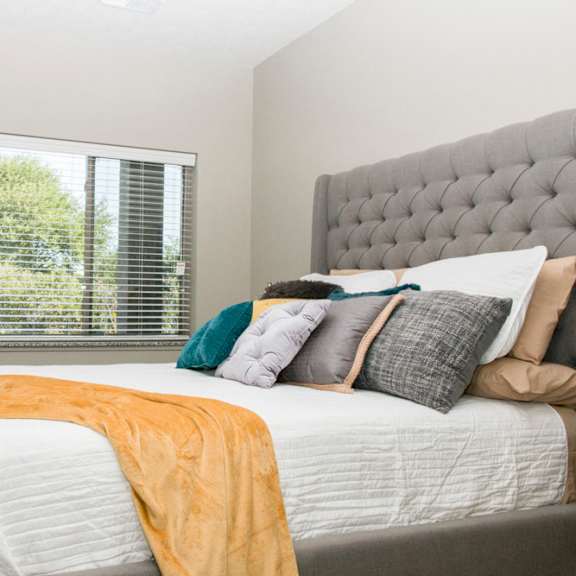 Thumbnail 10 of 13 A bedroom with a large bed and a window with blinds.