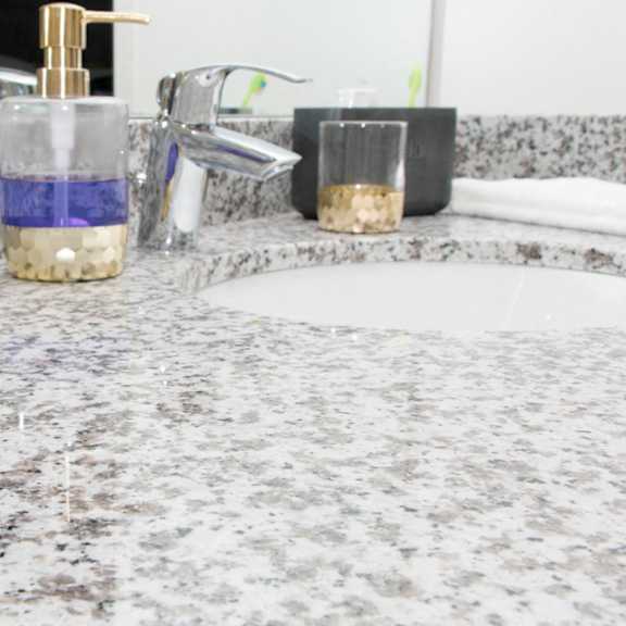 Thumbnail 12 of 13 A bathroom counter with a soap dispenser and a sink.