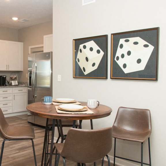 Thumbnail 8 of 13 A kitchen with a table and chairs and two paintings on the wall.
