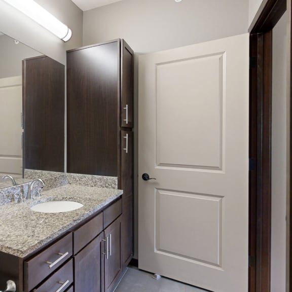 Thumbnail 14 of 19 a bathroom vanity with large mirror, light granite countertops, and dark cabinets