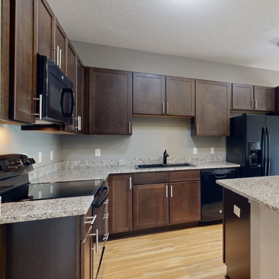 Thumbnail 5 of 19 a kitchen with dark cabinets, black appliances, and light granite countertops