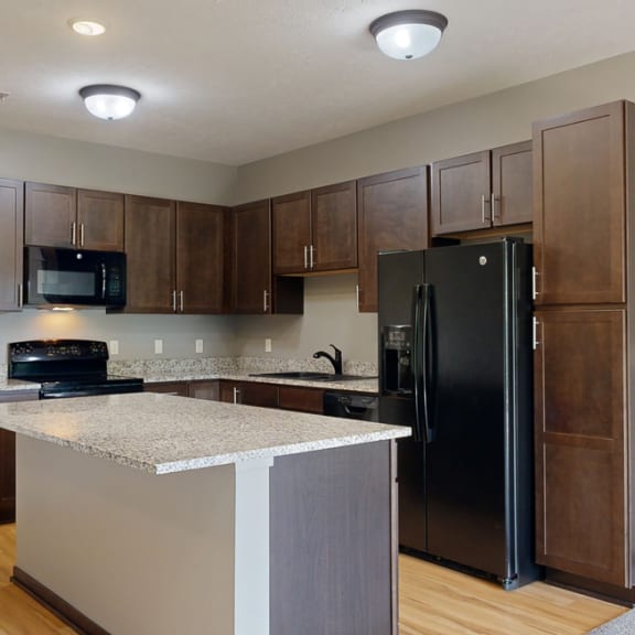 Thumbnail 4 of 19 a kitchen with dark cabinets, black appliances, and light granite countertops