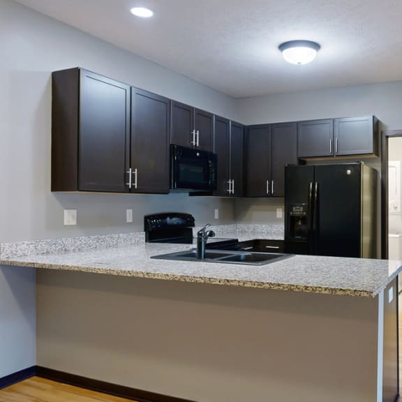 Thumbnail 4 of 17 a kitchen with dark cabinets and a granite counter top