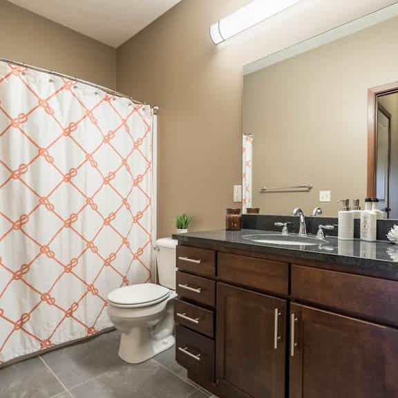 Thumbnail 15 of 15 A bathroom with a toilet, sink, and shower curtain.