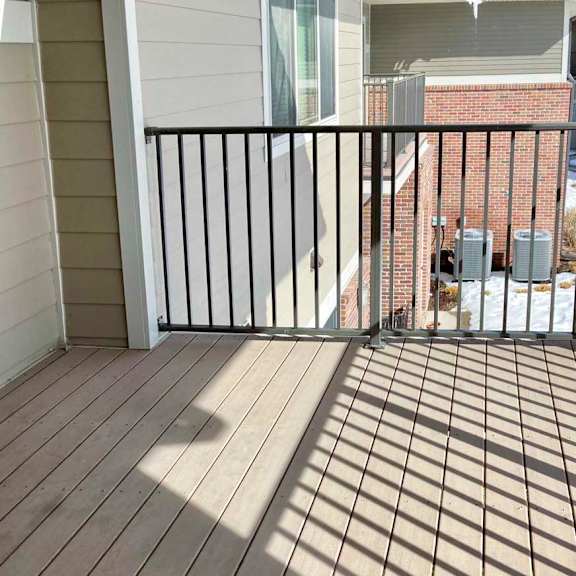 Thumbnail 10 of 16 A balcony with a black metal railing and wooden floor.