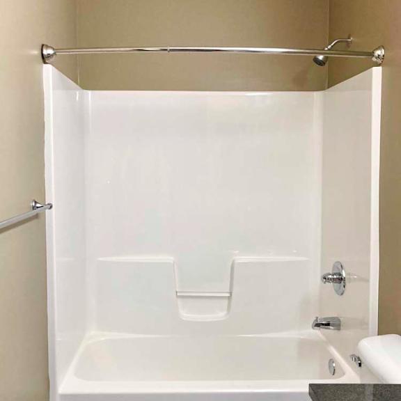 Thumbnail 17 of 19 A bathroom with a white tub shower with chrome fixtures.