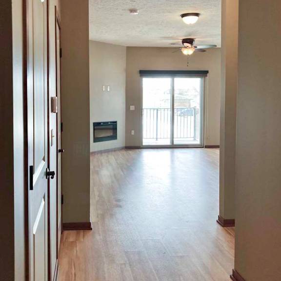 Thumbnail 3 of 19 A hallway with closets leading to an open living room.