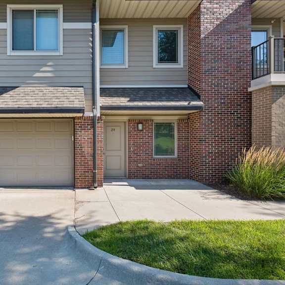 Thumbnail 16 of 16 Unit exterior with brick and gray siding, an attached two-car garage, covered entry, and upper-level balcony.