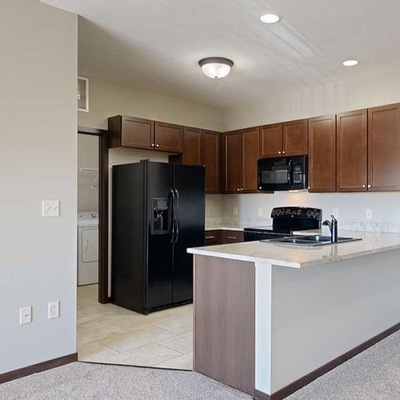 Thumbnail 5 of 22 a kitchen with granite countertops, black appliances, and bark brown cabinets