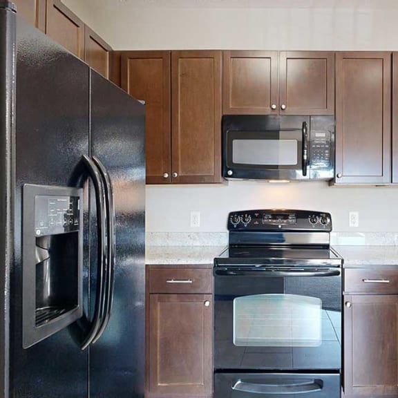 Thumbnail 6 of 22 a kitchen with black appliances, wooden cabinets, and granite countertops