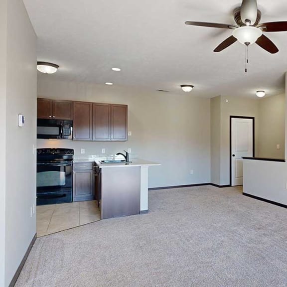 Thumbnail 10 of 22 a living room with a ceiling fan next to a kitchen and dining room, with a coat closet