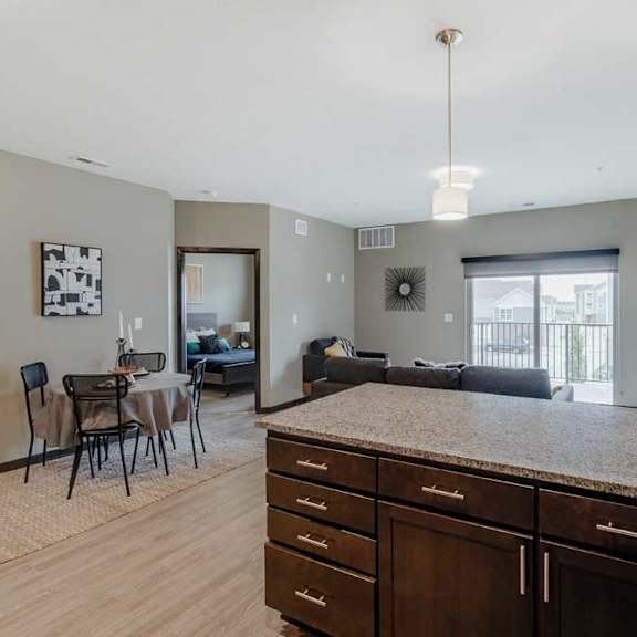 Thumbnail 6 of 17 A kitchen with dark wood cabinets and a granite countertop in front of a living room