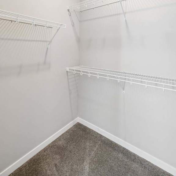 Thumbnail 40 of 44 Walk-in apartment closet with built-in wire shelving, carpeted flooring, recessed lighting, and generous hanging space for clothing and storage.