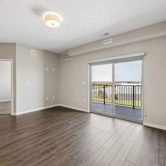 Thumbnail 27 of 36 Bright apartment bedroom with wood-style flooring, a large sliding glass door leading to a private balcony, and abundant natural light.